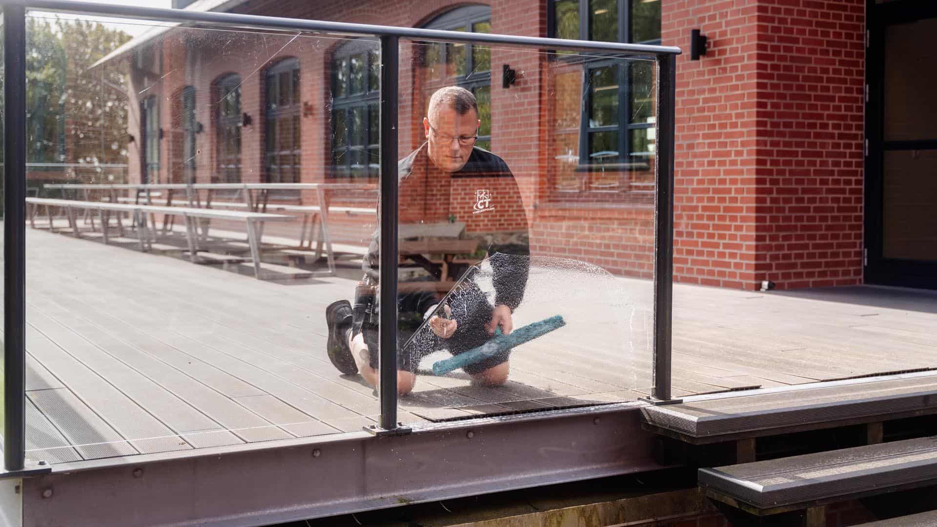 Vinduespudser fra CT vinduespolering udfører vinduespudsning til erhverv på terrasse